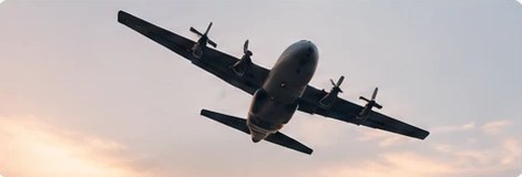 A C-130 cargo plane in flight at dusk